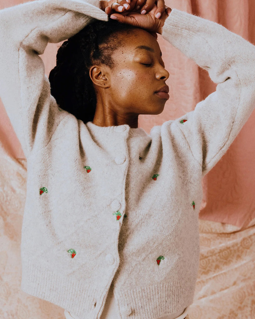 Luźny kardigan Maja HELMSTEDT o pudełkowym fasonie z okrągłym dekoltem i szerokimi rękawami. Haftowany ręcznie w uroczy motyw z drobnymi poziomkami i pszczołami. Zapinany na guziki obszyte dzianiną.