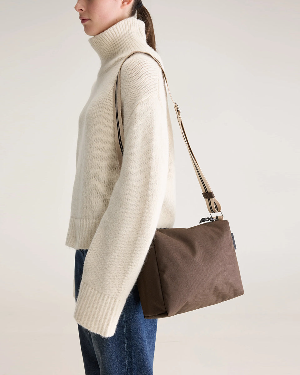 Zapinana na suwak torebka typu cross body Hobbes Dark Roast marki Bellerose z brązowego, matowego nylonu o fakturowanej powierzchni. Wyróżnia się prostokątnym kształtem, miękką konstrukcją oraz regulowanym paskiem w paski i silikonowym logo.&nbsp;