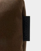 Zapinana na suwak torebka typu cross body Hobbes Dark Roast marki Bellerose z brązowego, matowego nylonu o fakturowanej powierzchni. Wyróżnia się prostokątnym kształtem, miękką konstrukcją oraz regulowanym paskiem w paski i silikonowym logo.&nbsp;