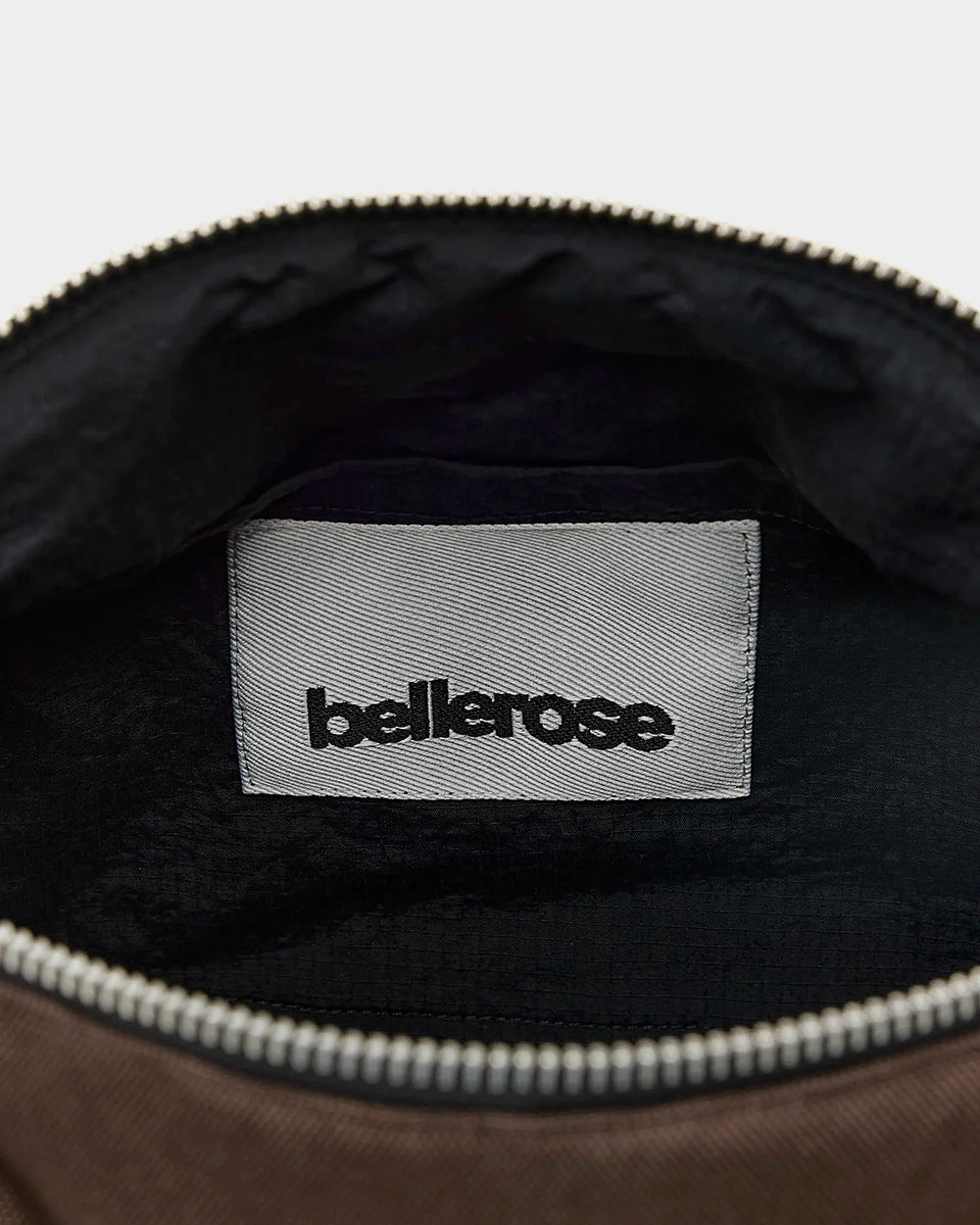 Zapinana na suwak torebka typu cross body Hobbes Dark Roast marki Bellerose z brązowego, matowego nylonu o fakturowanej powierzchni. Wyróżnia się prostokątnym kształtem, miękką konstrukcją oraz regulowanym paskiem w paski i silikonowym logo.&nbsp;