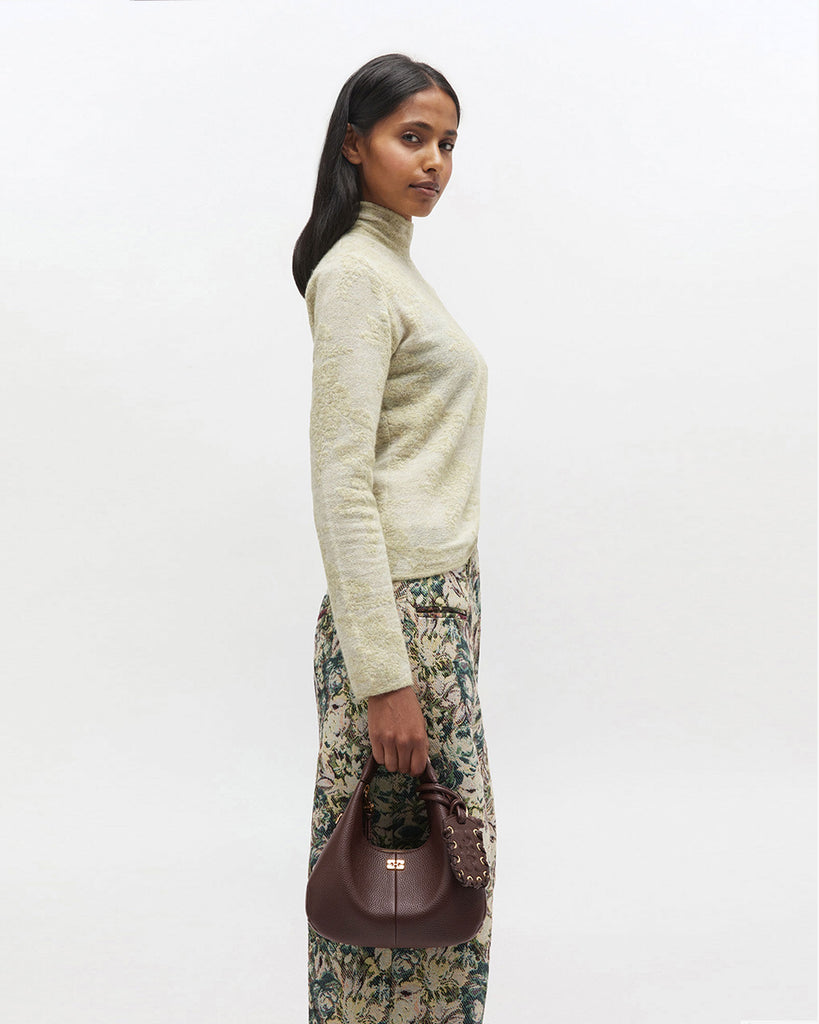 Mała, brązowa torebka w kształcie półksiężyca Hobo Mini Chicory Coffee z uchwytem i regulowanym, odpinanym paskiem oraz zapięciem na suwak. Z przodu posiada niewielki wypukły logotyp marki. Z tyłu, u dołu znajduje się wytłaczany napis GANNI. Do torebki dołączona jest lustrzana zawieszka. Wewnątrz posiada niewielką kieszonkę na najważniejsze drobiazgi takie jak klucze czy karta kredytowa.