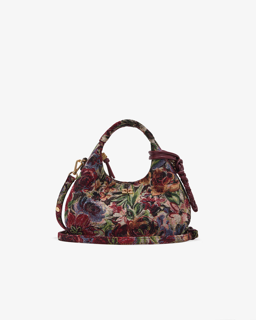 Mała torebka w kształcie półksiężyca Hobo Mini Tawny Port w kwiatowy print z uchwytem i regulowanym, odpinanym paskiem oraz zapięciem na suwak. Z przodu posiada niewielki wypukły logotyp marki. Z tyłu, u dołu znajduje się wytłaczany napis GANNI. Do torebki dołączona jest lustrzana zawieszka. Wewnątrz posiada niewielką kieszonkę na najważniejsze drobiazgi takie jak klucze czy karta kredytowa.&nbsp;