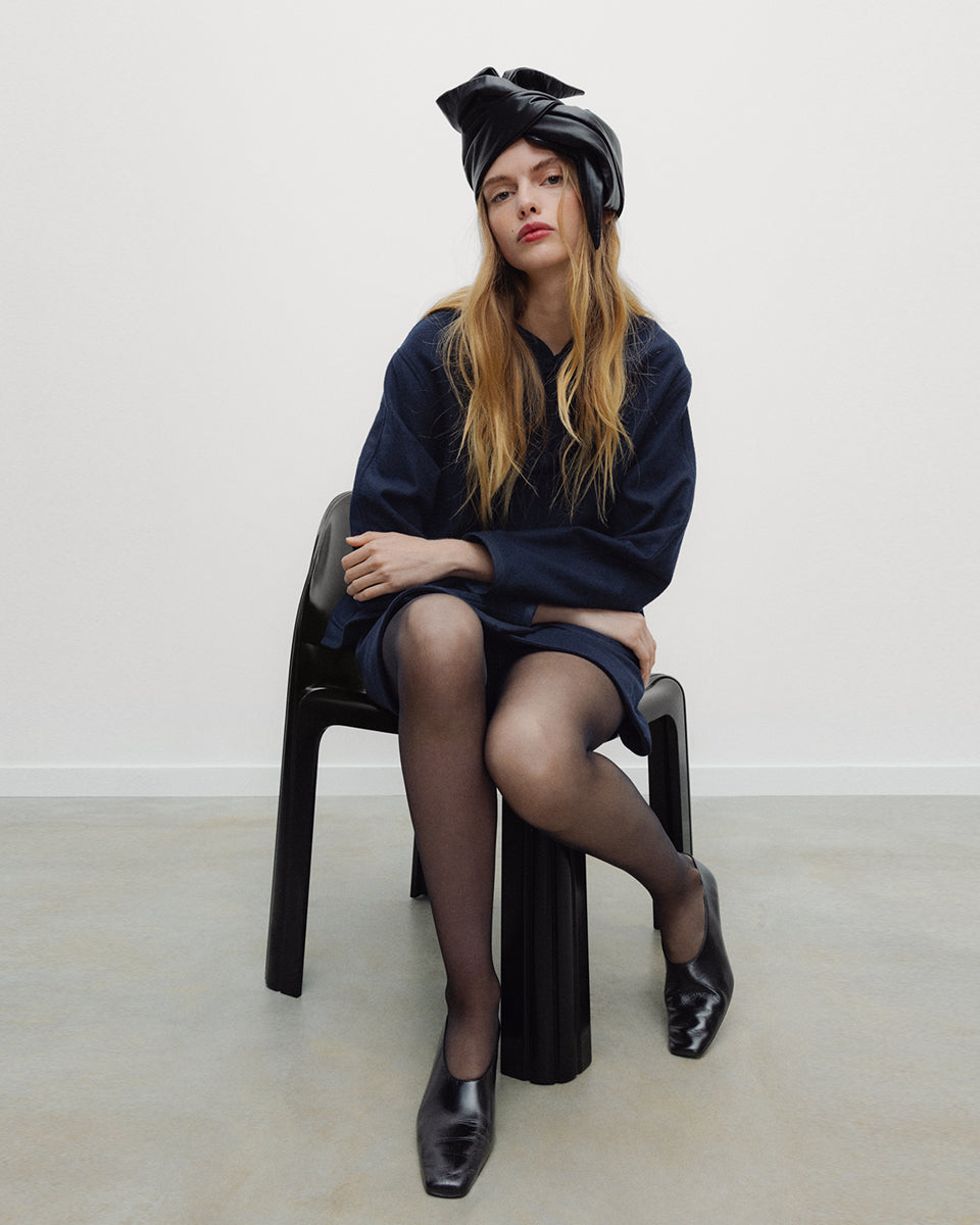Elegancka, ciemnogranatowa, krótka kurtka Indie Black Iris o fasonie inspirowanym stylem wschodnim. Model ma prosty krój z okrągłym dekoltem bez kołnierzyka oraz długie rękawy o swobodnej linii. Charakterystycznym elementem są ozdobne, tekstylne zapięcia typu chińskiego, zwane węzełkami, które biegną wzdłuż przedniej plisy. Kurtka posiada również dwie duże, naszywane kieszenie oraz zaokrąglone doły po bokach, co nadaje jej miękki, nowoczesny wygląd. Wykonana z mieszanki z wełną.

-Inspirowana stylem wschodn