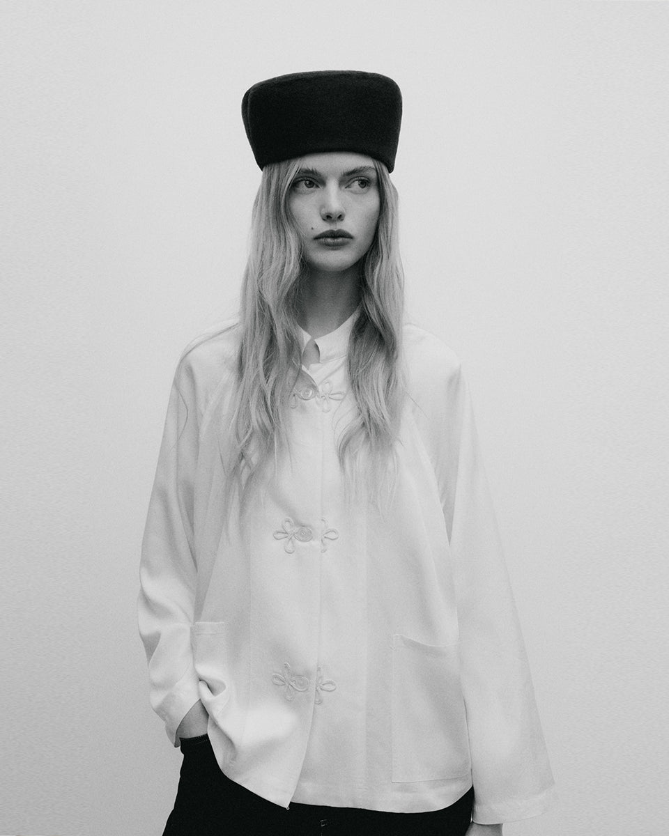 Elegancki, minimalistyczny kapelusz typu pillbox Indie TNS Black Iris wykonany z gładkiego, ciemnogranatowego filcu wełnianego. Jego konstrukcja wyróżnia się opływowym, zaokrąglonym kształtem, co nadaje mu nowoczesnego, a jednocześnie nawiązującego do stylu retro wyglądu. Kapelusz ściśle przylega do głowy, tworząc czystą, geometryczną linię, która subtelnie eksponuje rysy twarzy.&nbsp;