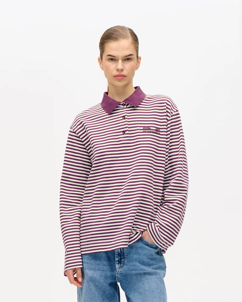 Oversizowa, bawełniana bluzka polo&nbsp;Jeanne Italian Plum Baum und Pferdgarten w paski. Posiada&nbsp;kołnierzyk, luźne, długie rękawy i prosty krój. Przy szyi zapinana na guziki. Nad lewą piersią bluzka ma&nbsp;niewielkie logo marki. Załóż ją do spódnicy midi lub prostych jeansów.