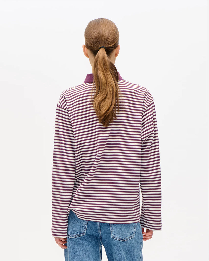 Oversizowa, bawełniana bluzka polo&nbsp;Jeanne Italian Plum Baum und Pferdgarten w paski. Posiada&nbsp;kołnierzyk, luźne, długie rękawy i prosty krój. Przy szyi zapinana na guziki. Nad lewą piersią bluzka ma&nbsp;niewielkie logo marki. Załóż ją do spódnicy midi lub prostych jeansów.