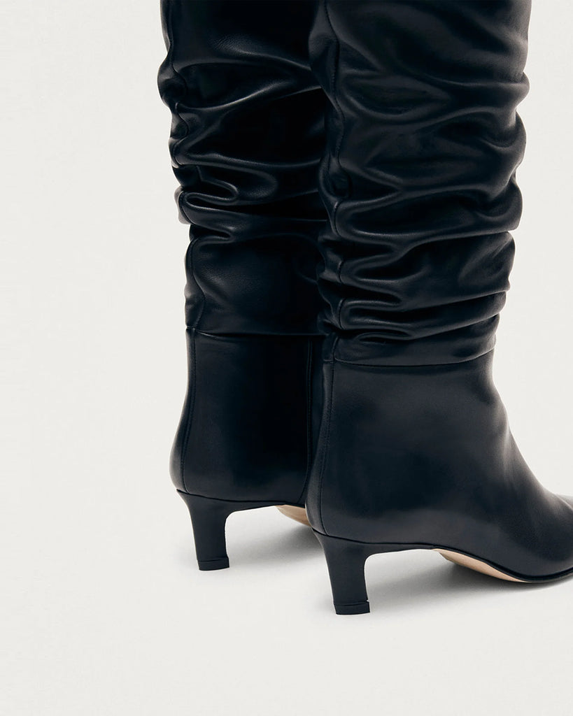 Czarne Kozaki ALOHAS Kalila Black Leather na obcasie typu kaczuszek. Kozaki do kolan wykonane z czarnej skóry z wydłużonymi, kwadratowymi noskami i niskim obcasem, który zapewnia wygodę. Efektowne marszczenia na cholewce dodają im charakteru, który przyciągnie uwagę każdej stylizacji.&nbsp;