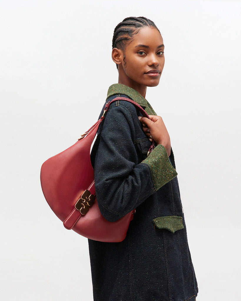 Ponadczasowa, czerwona torebka Kat Small 7077 GANNI Red Dahlia w stylu souffle o zaokrąglonym kształcie, z paskiem na ramię i detalami w kształcie D-ringów z boku. Posiada zapięcie z przodu, z charakterystycznym złotym detalem GANNI Butterfly. Ma jedną, główną kieszeń otwartą. Wykonana z opatentowanego przez markę, ekologicznego materiału bedącego połączeniem skóry z recyclingu oraz syntetycznych włókien. Uniwersalny rozmiar torebki sprawia, że będzie idealna zarówno na codzień, jak i na eleganckie okazje.&