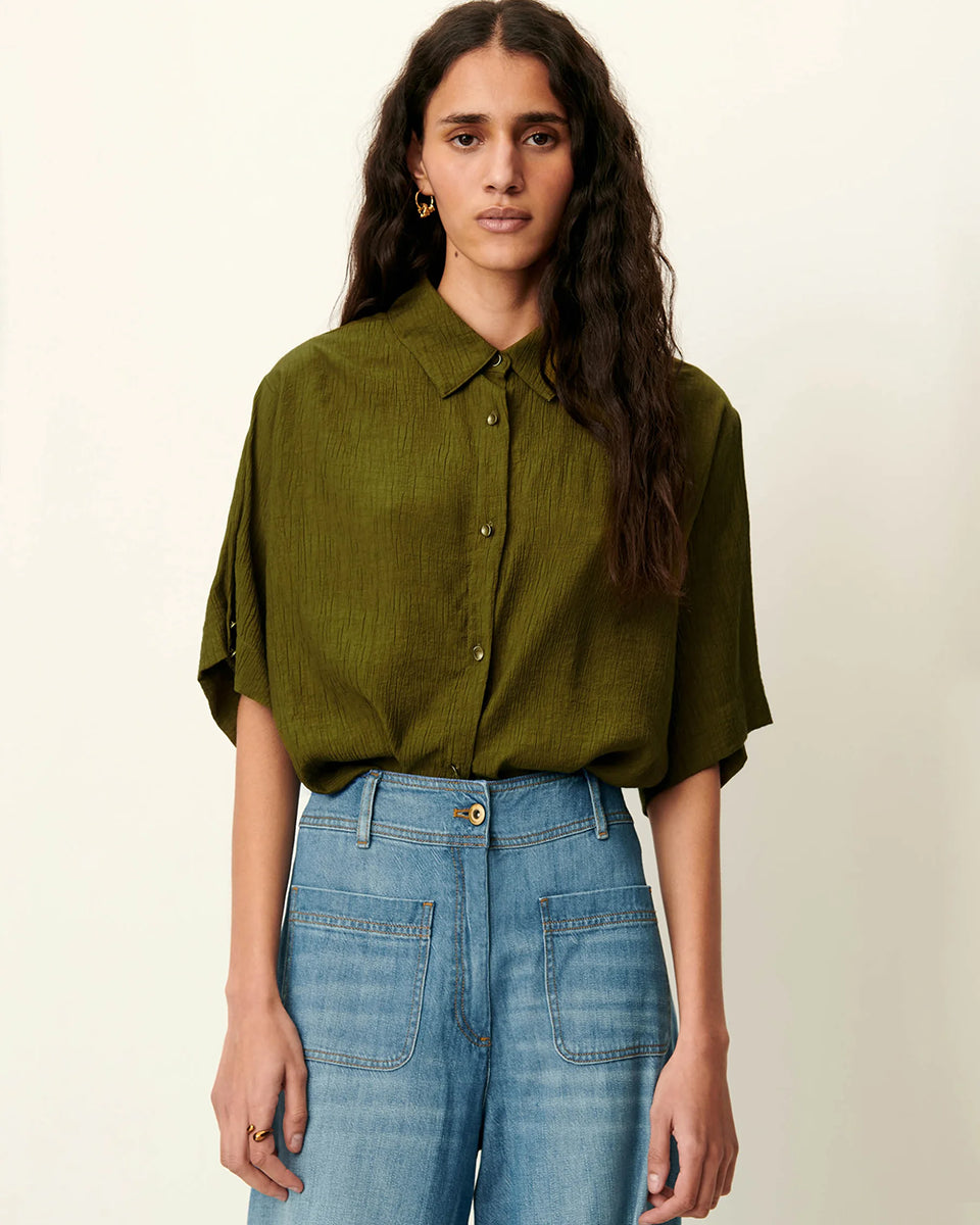 Luźna, krótka koszula Kayla Agave Green marki Sessun z klasycznym kołnierzykiem i krótkim rękawem z biżuteryjnymi guzikami przy mankietach. Zapinana z przodu na ozdobne guziki. Na plecach posiada płaskie zakładki, które dodają lekkości. Wykonana z mieszanki z wiskozą. To idealna propozycja na cieplejsze dni.&nbsp;

-Luźny, krótki fason

-Ozdobne guziki

-Zamów koszulę w swoim standardowym rozmiarze