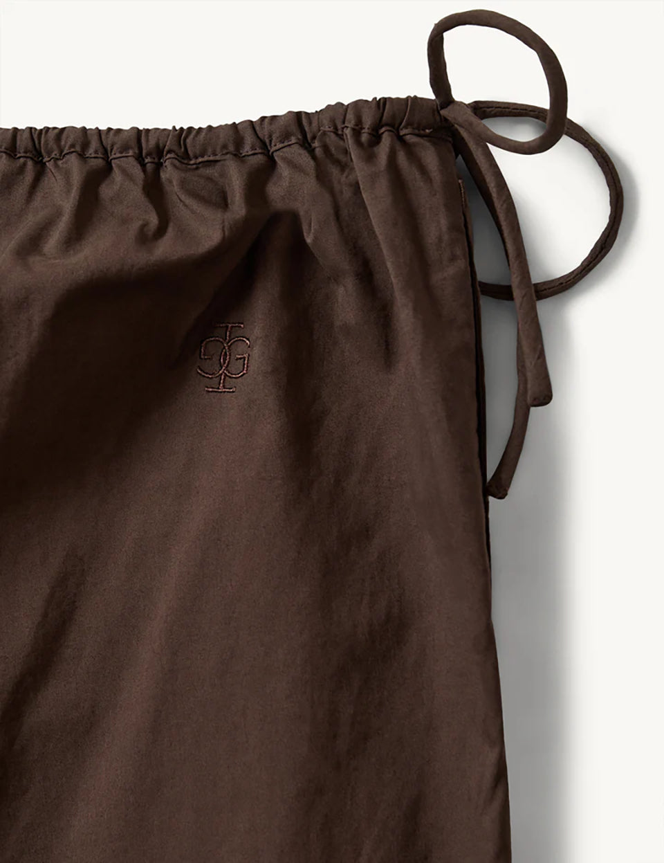 Luźne, proste, brązowe spodnie Kirsten Chocolate marki The Garment z szerokimi nogawkami i elastycznym pasem z regulacją na troczki po bokach. Nogawki wykończone są falistym brzegiem oraz delikatnym, ażurowym haftem tuż nad krawędzią. Wykonane z bawełny organicznej.&nbsp;

-Luźny, szeroki fason

-Elastyczny pas

-Faliste wykończenie&nbsp;

-Zamów spodnie w swoim standardowym rozmiarze
