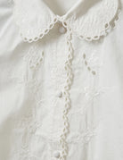 Romantyczna, klasyczna koszula Kirsten Collar White marki The Garment z zaokrąglonym kołnierzykiem z haftem angielskim i ażurowymi wycięciami. Posiada bardzo wysokie, eleganckie mankiety. Na piersiach i wzdłuż linii guzików znajdują się delikatne, kwiatowe hafty. Zapinana na drobne guziki. Brzeg koszuli oraz listwa guzikowa wykończone są falistym brzegiem. Wykonana z bawełny organicznej.

-Ozdobiona haftem angielskim

-Faliste brzegi

-Zamów koszulę w swoim standardowym rozmiarze