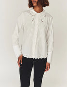 Romantyczna, klasyczna koszula Kirsten Collar White marki The Garment z zaokrąglonym kołnierzykiem z haftem angielskim i ażurowymi wycięciami. Posiada bardzo wysokie, eleganckie mankiety. Na piersiach i wzdłuż linii guzików znajdują się delikatne, kwiatowe hafty. Zapinana na drobne guziki. Brzeg koszuli oraz listwa guzikowa wykończone są falistym brzegiem. Wykonana z bawełny organicznej.

-Ozdobiona haftem angielskim

-Faliste brzegi

-Zamów koszulę w swoim standardowym rozmiarze