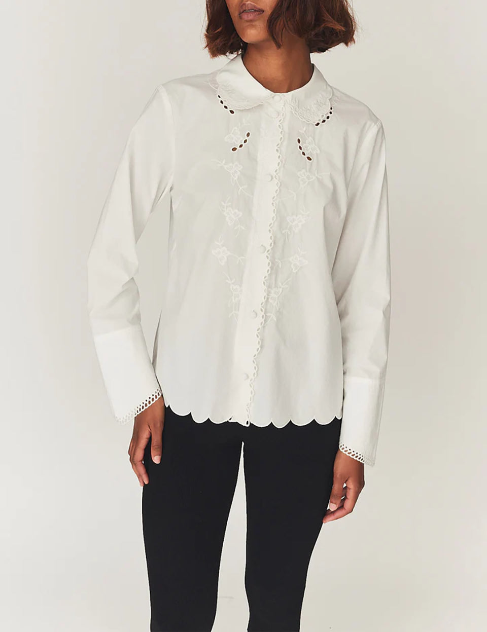 Romantyczna, klasyczna koszula Kirsten Collar White marki The Garment z zaokrąglonym kołnierzykiem z haftem angielskim i ażurowymi wycięciami. Posiada bardzo wysokie, eleganckie mankiety. Na piersiach i wzdłuż linii guzików znajdują się delikatne, kwiatowe hafty. Zapinana na drobne guziki. Brzeg koszuli oraz listwa guzikowa wykończone są falistym brzegiem. Wykonana z bawełny organicznej.

-Ozdobiona haftem angielskim

-Faliste brzegi

-Zamów koszulę w swoim standardowym rozmiarze