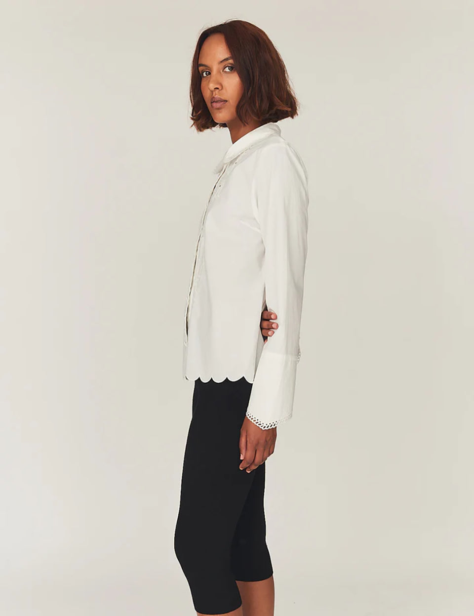 Romantyczna, klasyczna koszula Kirsten Collar White marki The Garment z zaokrąglonym kołnierzykiem z haftem angielskim i ażurowymi wycięciami. Posiada bardzo wysokie, eleganckie mankiety. Na piersiach i wzdłuż linii guzików znajdują się delikatne, kwiatowe hafty. Zapinana na drobne guziki. Brzeg koszuli oraz listwa guzikowa wykończone są falistym brzegiem. Wykonana z bawełny organicznej.

-Ozdobiona haftem angielskim

-Faliste brzegi

-Zamów koszulę w swoim standardowym rozmiarze