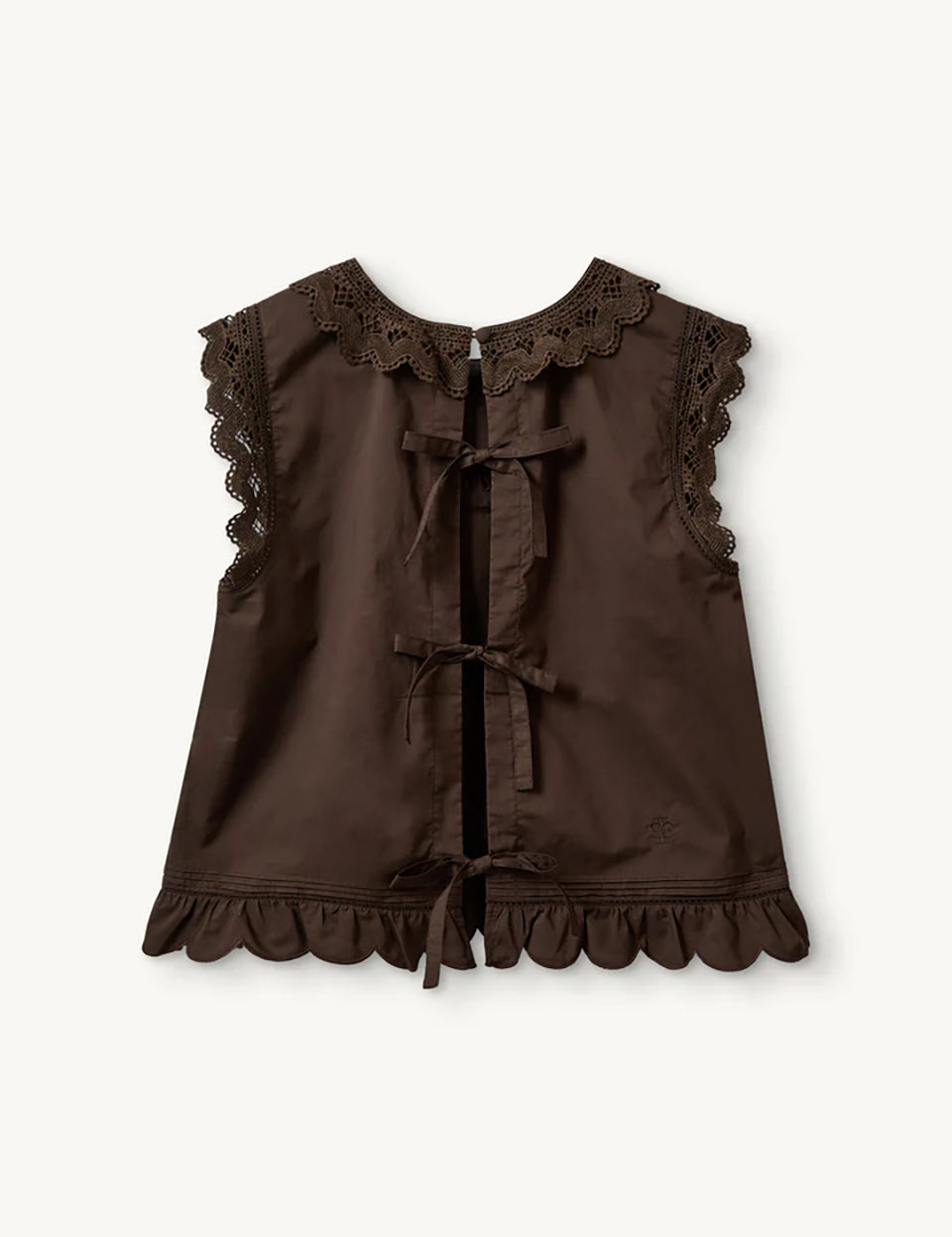 Swobodny, bawełniany top Kirsten Cloth Chocolate marki The Garment o lekko trapezowym kształcie. Ma okrągły dekolt wykończony szerokim, koronkowym kołnierzykiem. Podobne obszycia znajdują się wokół ramion, co tworzy efekt falbanki. Na piersi widoczny jest subtelny, ażurowy haft. Plecy są rozcięte i wiązane na trzy kokardki. Dół wykończony jest falistym brzegiem.

-Ażurowe hafty

-Tył wiązany na kokardki

-Bawełna organiczna

-Zamów top w swoim standardowym rozmiarze