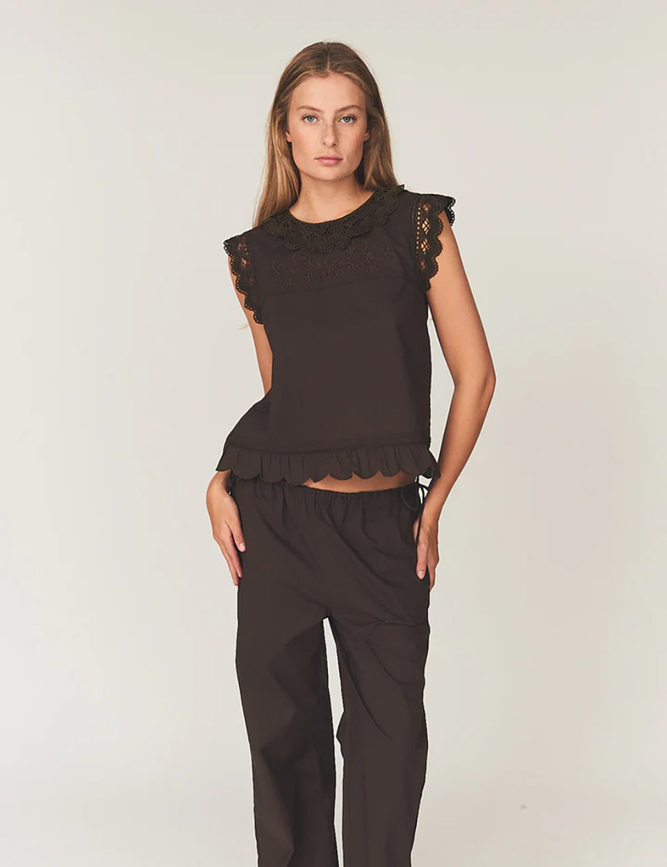 Swobodny, bawełniany top Kirsten Cloth Chocolate marki The Garment o lekko trapezowym kształcie. Ma okrągły dekolt wykończony szerokim, koronkowym kołnierzykiem. Podobne obszycia znajdują się wokół ramion, co tworzy efekt falbanki. Na piersi widoczny jest subtelny, ażurowy haft. Plecy są rozcięte i wiązane na trzy kokardki. Dół wykończony jest falistym brzegiem.

-Ażurowe hafty

-Tył wiązany na kokardki

-Bawełna organiczna

-Zamów top w swoim standardowym rozmiarze