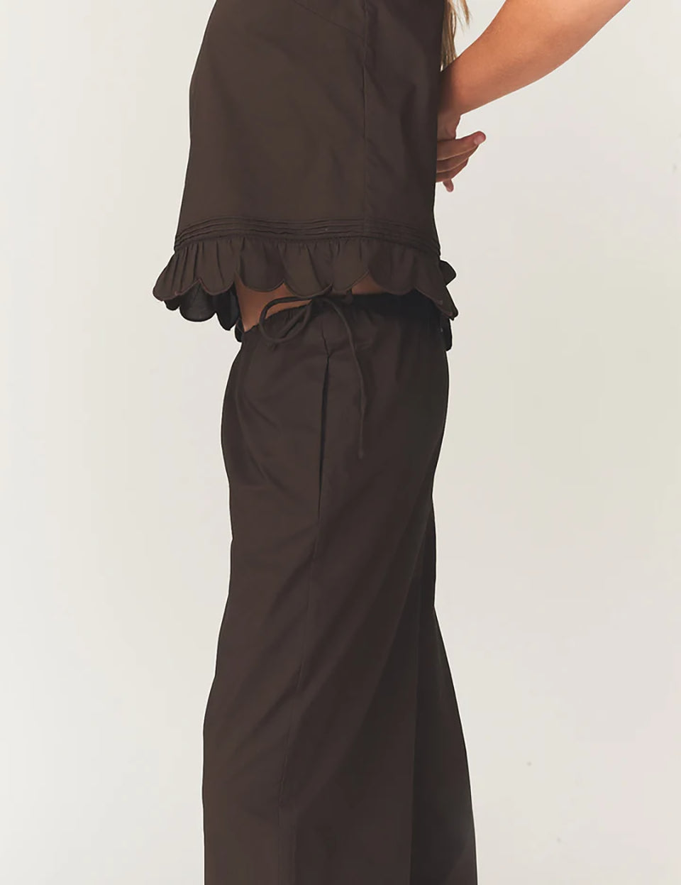 Swobodny, bawełniany top Kirsten Cloth Chocolate marki The Garment o lekko trapezowym kształcie. Ma okrągły dekolt wykończony szerokim, koronkowym kołnierzykiem. Podobne obszycia znajdują się wokół ramion, co tworzy efekt falbanki. Na piersi widoczny jest subtelny, ażurowy haft. Plecy są rozcięte i wiązane na trzy kokardki. Dół wykończony jest falistym brzegiem.

-Ażurowe hafty

-Tył wiązany na kokardki

-Bawełna organiczna

-Zamów top w swoim standardowym rozmiarze