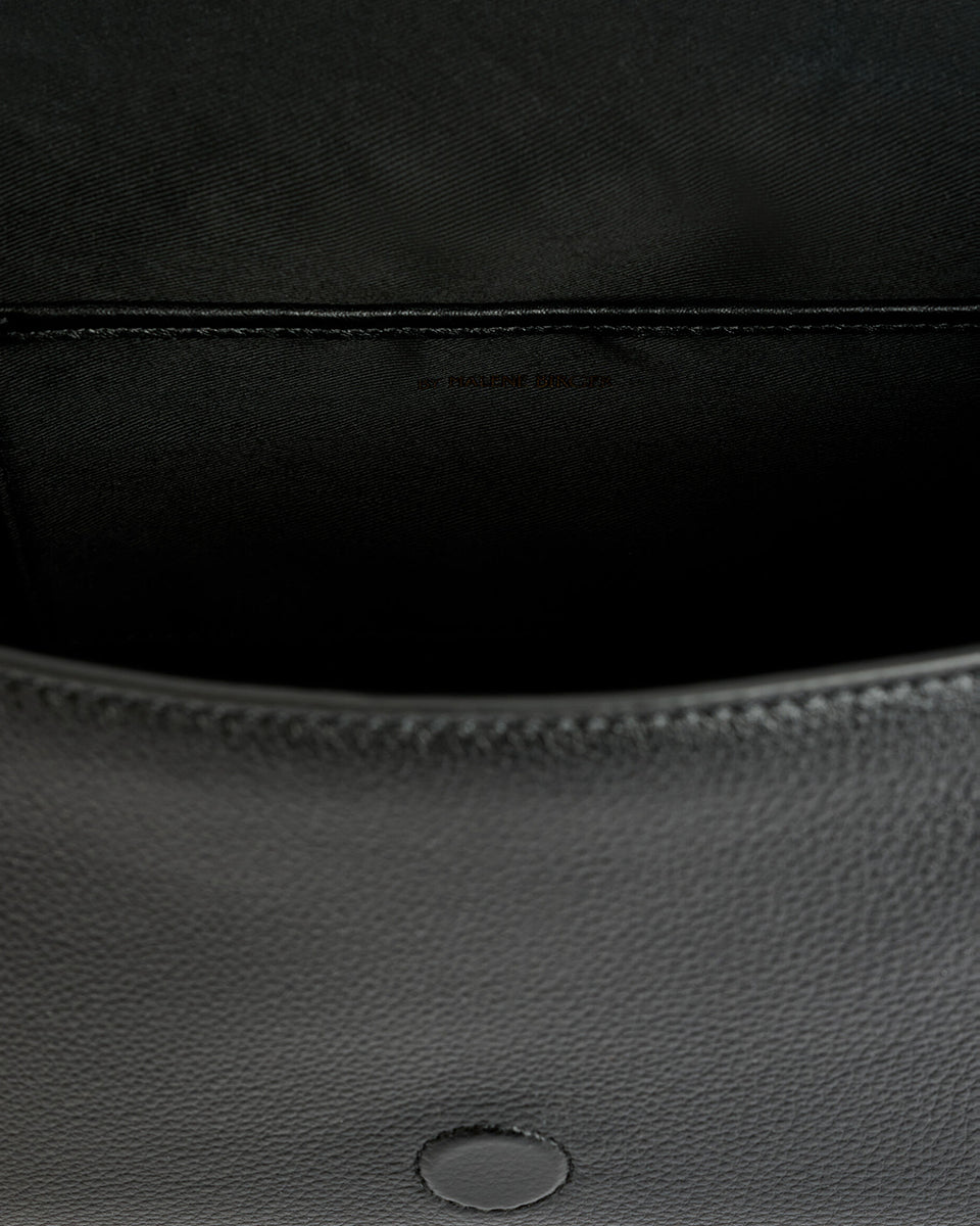 Minimalistyczna, elegancka torebka Lellie Black By Malene Birger o prostokątnym kształcie z lekko zaokrąglonymi bokami. Zapinana na zatrzask magnetyczny. Posiada krótki, szeroki pasek na ramię, który ozdobiony jest złotymi elementami. Na środku klapy umieszczono metalowy emblemat marki w kolorze złotym. W środku znajduje się mała kieszonka na drobiazgi, a całość wykończona jest gładką podszewką. Wykonana w 100% ze skóry.&nbsp;