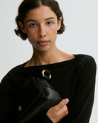 Minimalistyczna, elegancka torebka Lellie Black By Malene Birger o prostokątnym kształcie z lekko zaokrąglonymi bokami. Zapinana na zatrzask magnetyczny. Posiada krótki, szeroki pasek na ramię, który ozdobiony jest złotymi elementami. Na środku klapy umieszczono metalowy emblemat marki w kolorze złotym. W środku znajduje się mała kieszonka na drobiazgi, a całość wykończona jest gładką podszewką. Wykonana w 100% ze skóry.&nbsp;