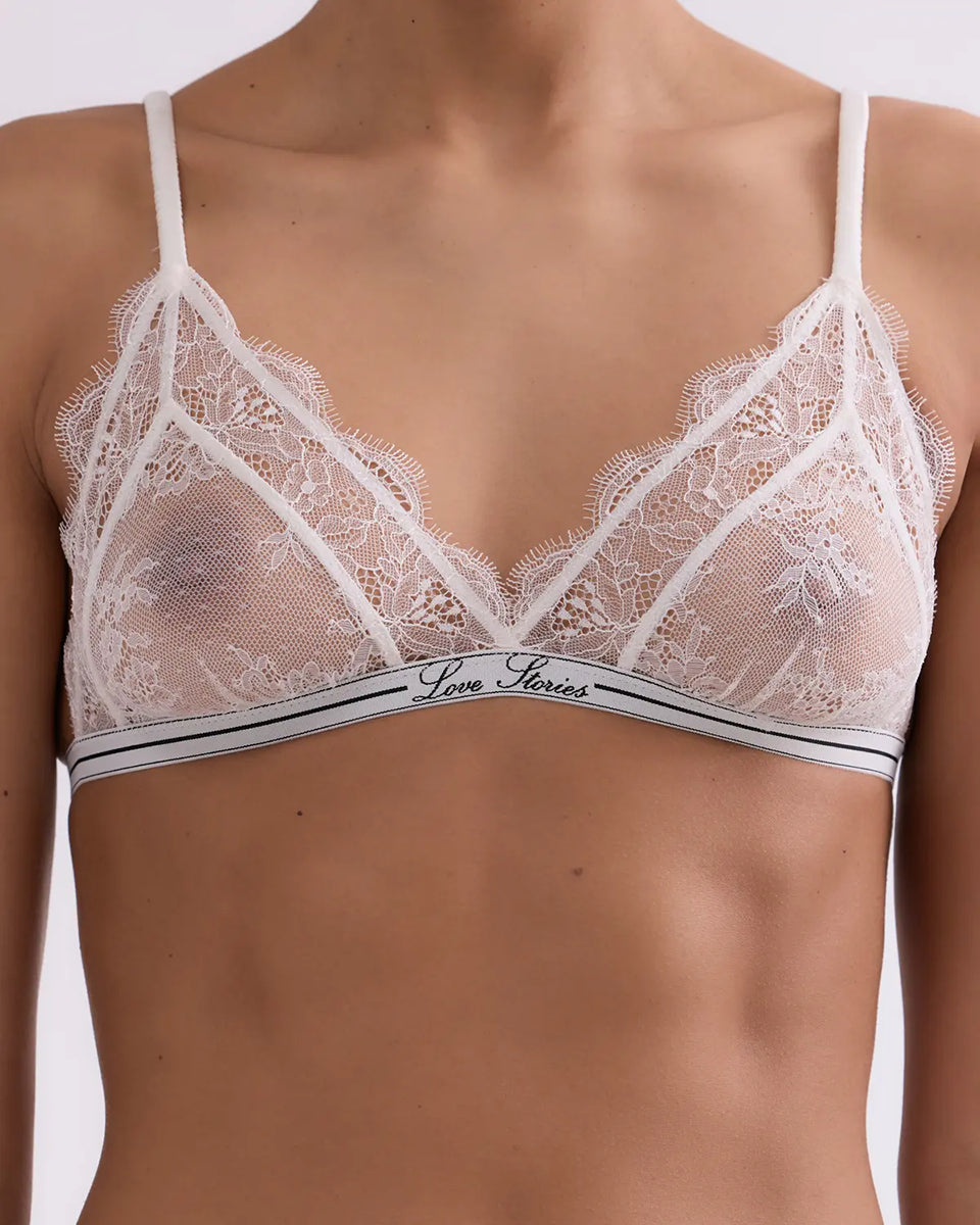 Delikatny, miękki stanik z trójkątnymi miseczkami Love Lace Love Stories. Wykonany z białej, koronkowej tkaniny. Stanik posiada cienką gumę pod biustem z logo marki oraz&nbsp;regulowane, marszczone ramiączka. Zapinany na plecach za pomocą haftek.