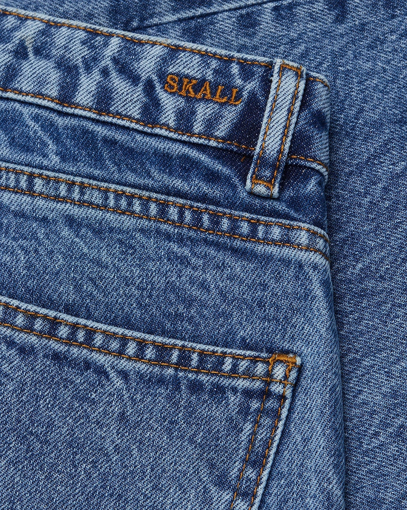 Luźne, niebieskie jeansy Allison SKALL ze średnim stanem i prostą, luźną, lekko skróconą nogawką. Spodnie mają pięć kieszeni i szlufki na pasek. Zapinane są na guzik i zamek błyskawiczny. Wykonane z organicznej, certyfikowanej bawełny z delikatnym efektem "sprania". Idea