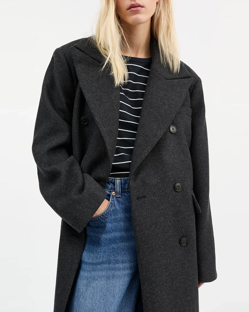 Oversizowy, dwurzędowy, wełniany płaszcz David SKALL z szerokimi ramionami i długimi rękawami. Płaszcz ma prosty krój i długość przed kostki. Inspirowany modą męską. Posiada jedną kieszonkę na lewej piersi i dwie, przednie kieszenie z klapkami.