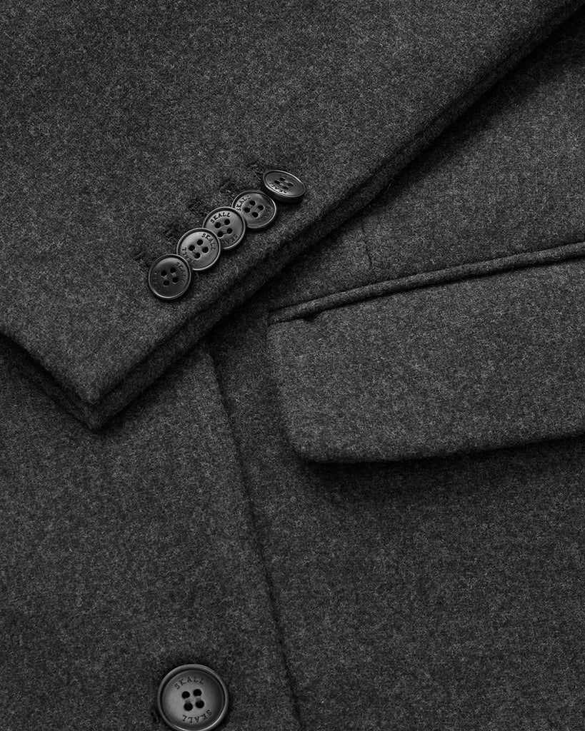 Oversizowy, dwurzędowy, wełniany płaszcz David SKALL z szerokimi ramionami i długimi rękawami. Płaszcz ma prosty krój i długość przed kostki. Inspirowany modą męską. Posiada jedną kieszonkę na lewej piersi i dwie, przednie kieszenie z klapkami.