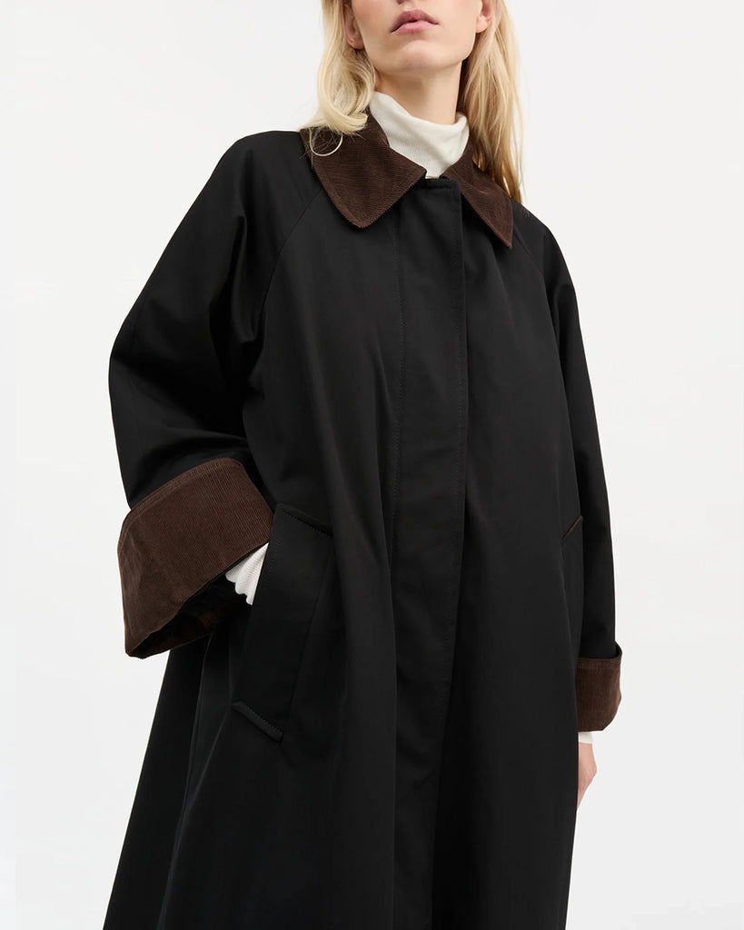 Oversizowy, przejściowy, inspirowany stylem brytyjskim płaszcz Gaby SKALL z dużym kołnierzykiem obszytym brązowym sztruksem i z szerokimi, wywijanymi rękawami ze sztruksowym obszyciem od wewnątrz mankietów. Płaszcz posiada dwie, boczne kieszenie i rozcięcie u dołu z tyłu.