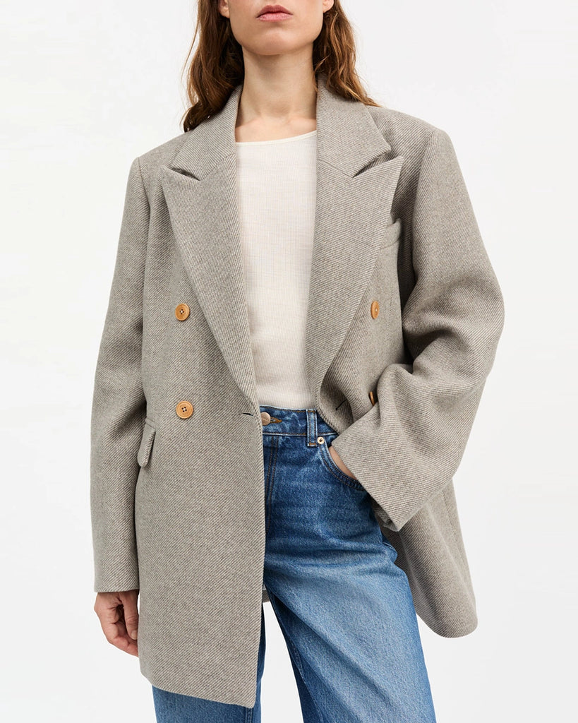 Gruba, długa marynarka z wełny w drobne, skośne prążki Mick SKALL zapinana na dwa rzędy guzików. Posiada prosty krój i długość za biodra. Marynarka ma duży kołnierz, niewielką kieszonkę nad lewą piersią i dwie, przednie kieszenie z klapkami. Przy mankietach zapinana na rząd drobnych guzików.