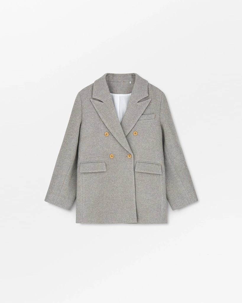 Gruba, długa marynarka z wełny w drobne, skośne prążki Mick SKALL zapinana na dwa rzędy guzików. Posiada prosty krój i długość za biodra. Marynarka ma duży kołnierz, niewielką kieszonkę nad lewą piersią i dwie, przednie kieszenie z klapkami. Przy mankietach zapinana na rząd drobnych guzików.