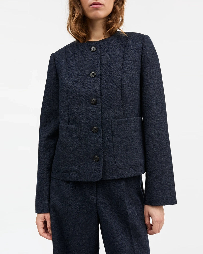 Klasyczna, krótka, wełniana marynarka Mona SKALL z okrągłym dekoltem. Zapinana na guziki. Z przodu posiada dwie, prostokątne kieszenie.