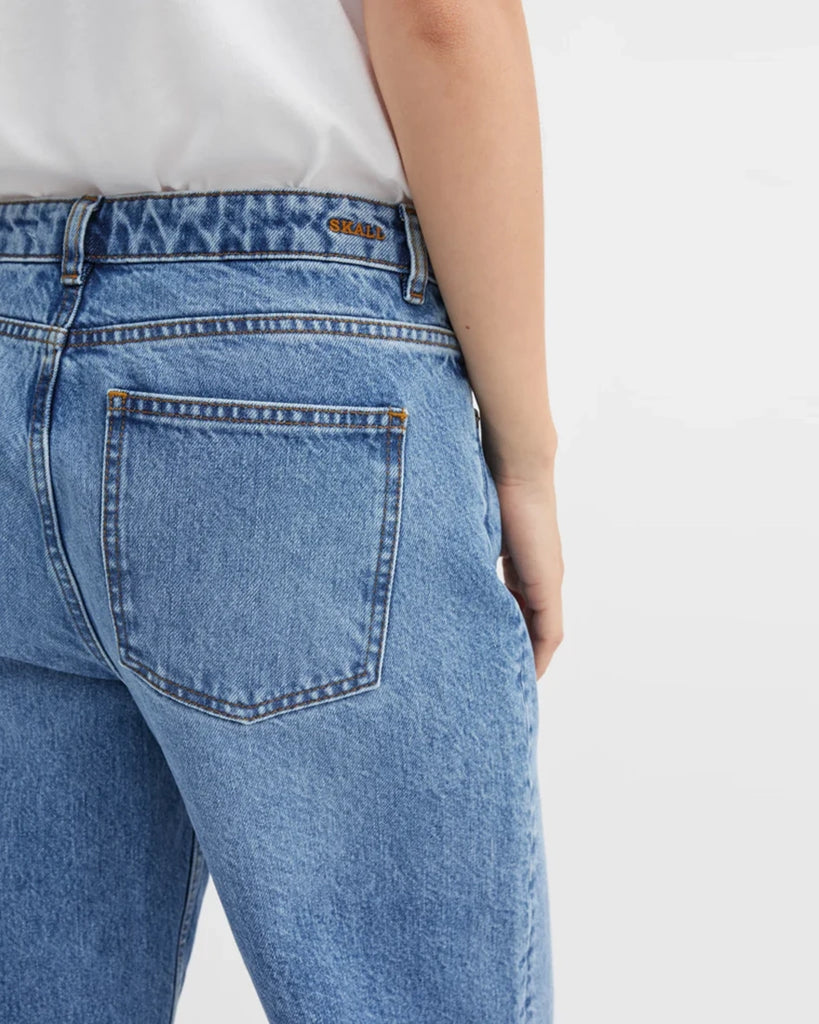 Luźne, niebieskie jeansy Allison SKALL ze średnim stanem i prostą, luźną, lekko skróconą nogawką. Spodnie mają pięć kieszeni i szlufki na pasek. 