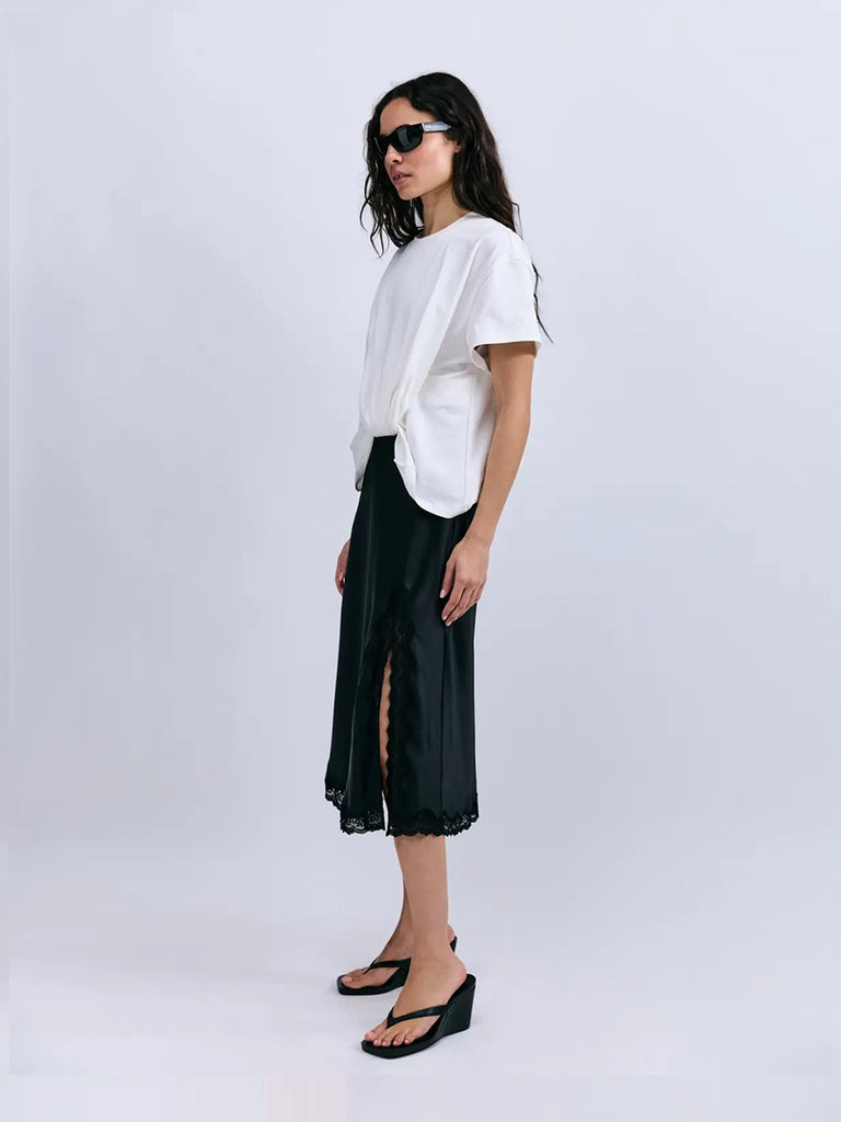 Luźna, warstwowa sukienka Ann Love Stories złożona z dwóch, połączonych ze sobą elementów - marszczonego, oversizowego t-shirtu i satynowej spódnicy midi. Spódnica wykończona jest koronką i posiada rozcięcie