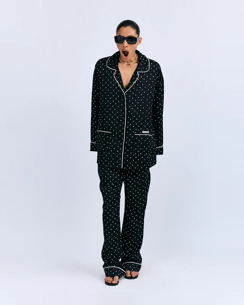 Oversizowa, piżamowa koszula Cedric Love Stories z lejącej, satynowej tkaniny w drobny, kwiatkowy print. Posiada dekolt w kształcie litery V, kołnierzyk i szerokie, długie rękawy. Zapinana na guziki. Obszyta cienką, błękitną lamówką. Koszula ma dwie, przednie kieszenie. Na prawej kieszeni znajduje się niewielka naszywka z logo marki