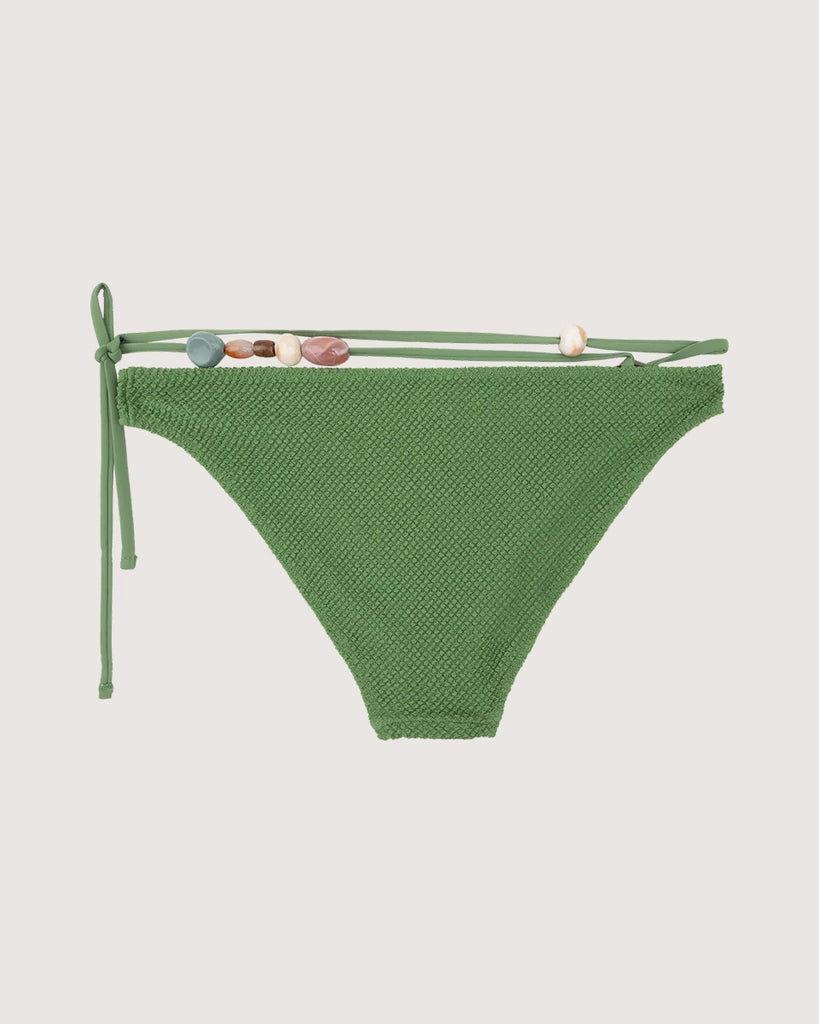 Dół od bikini Coral z dekoracyjnym, szylkretowym kółkiem na biodrze i odwiązywanym sznurkiem z kolorowymi koralikami o nieregularnej wielkości. 