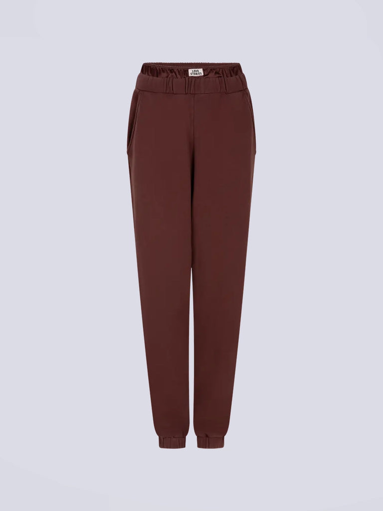 Luźne spodnie dresowe Donna Love Stories z wysokim stanem i zwężaną u dołu nogawką zakończoną ściągaczami. Elastyczne w pasie. Spodnie posiadają wszytą atrapę, satynowych bokserek oraz dwie, boczne kieszenie. Na tylnej kieszeni posiadają haftowany napis z nazwą marki. 