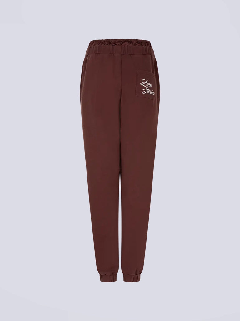 Luźne spodnie dresowe Donna Love Stories z wysokim stanem i zwężaną u dołu nogawką zakończoną ściągaczami. Elastyczne w pasie. Spodnie posiadają wszytą atrapę, satynowych bokserek oraz dwie, boczne kieszenie. Na tylnej kieszeni posiadają haftowany napis z nazwą marki. 