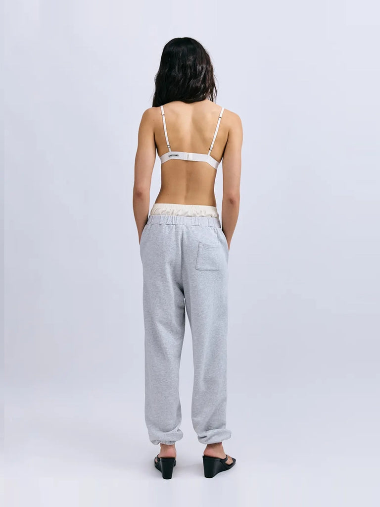 Luźne, szare spodnie dresowe Donna Love Stories z wysokim stanem i zwężaną u dołu nogawką zakończoną ściągaczami. Elastyczne w pasie. Spodnie posiadają wszytą atrapę, satynowych bokserek oraz dwie, boczne kieszenie