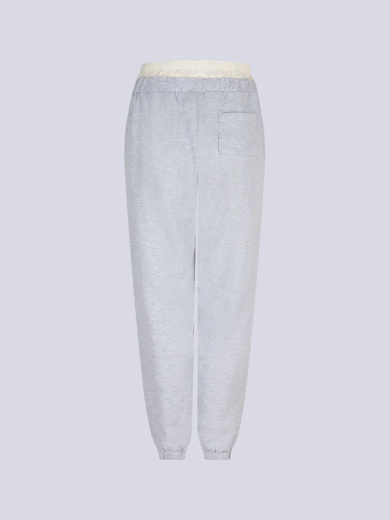 Luźne, szare spodnie dresowe Donna Love Stories z wysokim stanem i zwężaną u dołu nogawką zakończoną ściągaczami. Elastyczne w pasie. Spodnie posiadają wszytą atrapę, satynowych bokserek oraz dwie, boczne kieszenie
