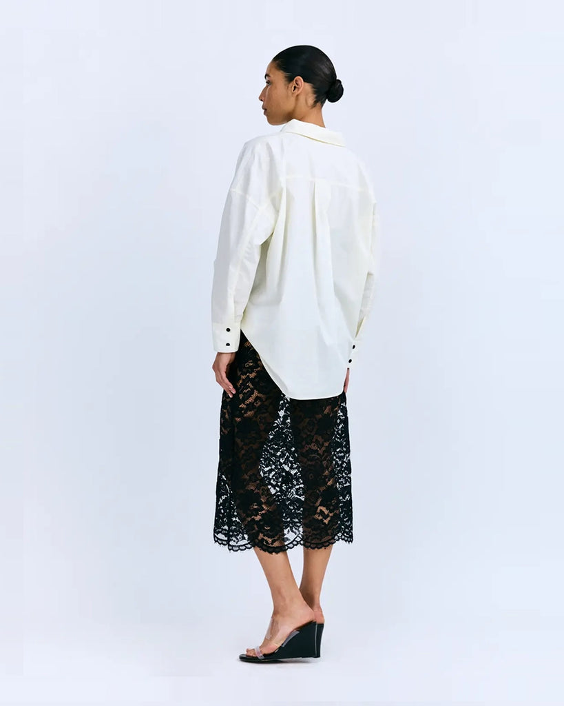 Sukienka midi Joey Love Stories z koszulową, luźną górą i transparentym, koronkowym dołem. Posiada kołnierzyk, opadające ramiona, kieszonkę z naszywką z logo marki i długie rękawy z mankietami. Zapinana na guziki. Sukienka ma długość do połowy łydki. Ma wszyte zakrywające majtki. 