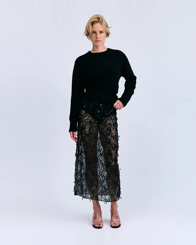 Czarna, transparentna, koronkowa spódnica midi Mia Love Stories z wysokim stanem i elastyczną talią. Posiada długość przed kostki. Idealna do luźnego swetra lub oversizowej koszuli.