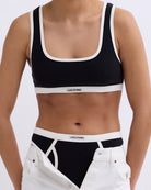 Miękki sportowy stanik top Rika Love Love Stories na grubych ramiączkach. Wykonany z miękkiej tkaniny z prążkowaną fakturą i białą, grubą lamówką. Na gumie pod biustem posiada niewielką naszywkę z logo marki.&nbsp;