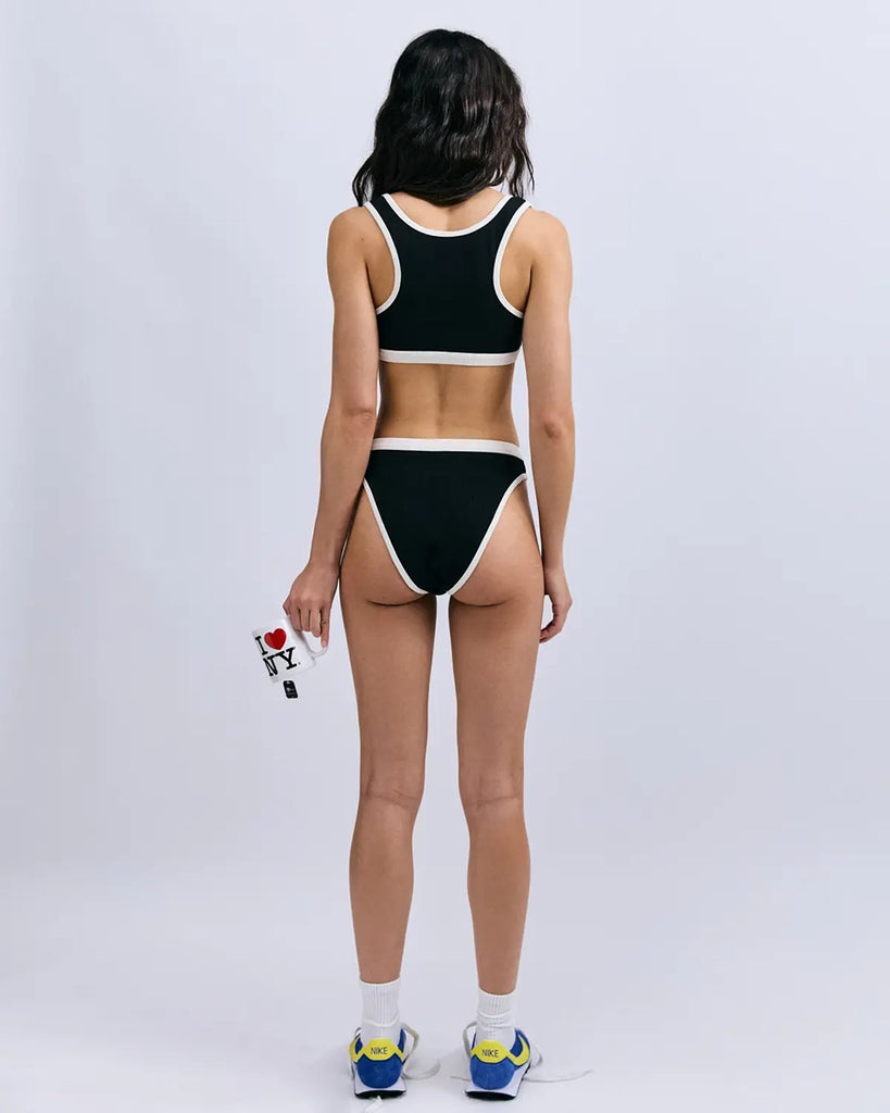 Miękki sportowy stanik top Rika Love Love Stories na grubych ramiączkach. Wykonany z miękkiej tkaniny z prążkowaną fakturą i białą, grubą lamówką. Na gumie pod biustem posiada niewielką naszywkę z logo marki.&nbsp;