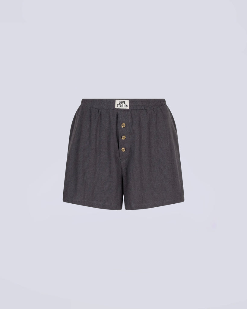 Luźne, ciemnoszare szorty w typie bokserek Sunday Love Stories ze średnim stanem i elastyczną talią. Z przodu posiadają niewielką naszywkę z logo marki i imitację rozporka z guzikami. Wykonane z bardzo miękkiej i oddychającej tkaniny.&nbsp;