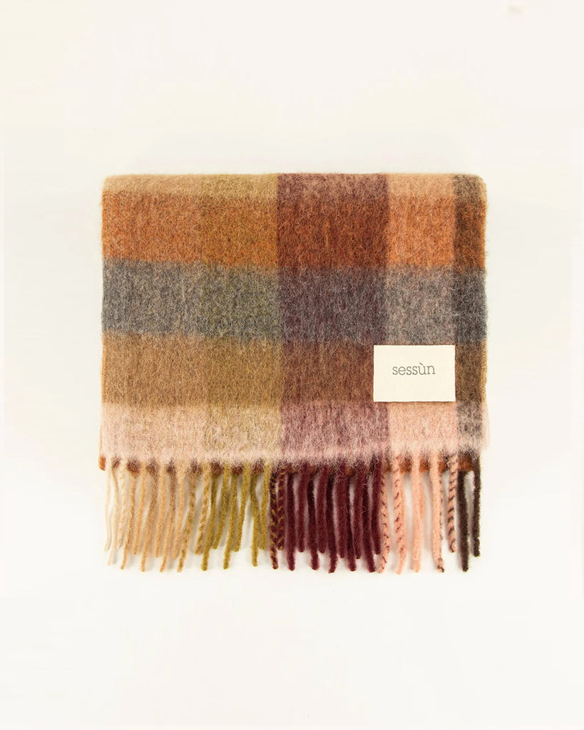 Ciepły, duży szalik Lucio Navyrust francuskiej marki Sessun w wielokolorową kratę, z frędzlami na brzegach. W prawym dolnym rogu posiada haftowaną metkę z logo marki. Wykonany z miękkiej dzianiny z alpaką. Idealnie sprawdzi się do jesienno-zimowych stylizacji.