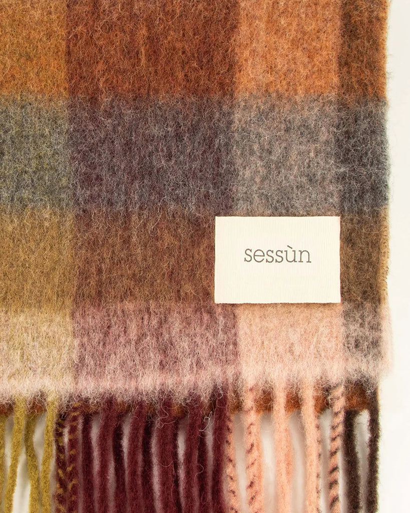 Ciepły, duży szalik Lucio Navyrust francuskiej marki Sessun w wielokolorową kratę, z frędzlami na brzegach. W prawym dolnym rogu posiada haftowaną metkę z logo marki. Wykonany z miękkiej dzianiny z alpaką. Idealnie sprawdzi się do jesienno-zimowych stylizacji.