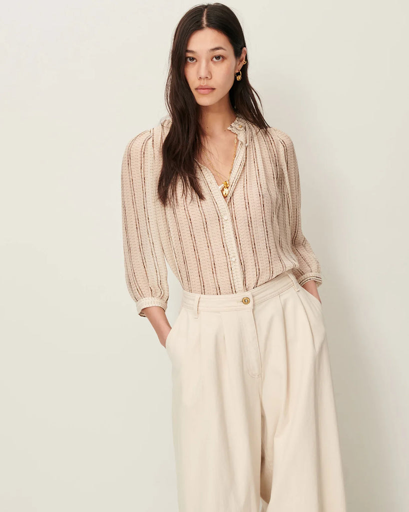 Efektowna, romantyczna Bluzka Lylee Whiplumikat francuskiej marki Sessun w drobne, metaliczne paski, z falbaniastym kołnierzykiem i szerokimi rękawami 3/4. Zapinana na guziki, z ozdobnym guzikiem przy kołnierzyku. Posiada marszczenia z przodu.