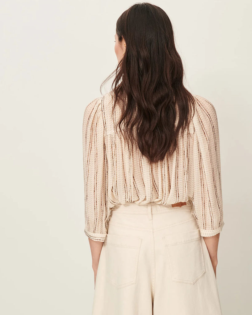 Efektowna, romantyczna Bluzka Lylee Whiplumikat francuskiej marki Sessun w drobne, metaliczne paski, z falbaniastym kołnierzykiem i szerokimi rękawami 3/4. Zapinana na guziki, z ozdobnym guzikiem przy kołnierzyku. Posiada marszczenia z przodu.