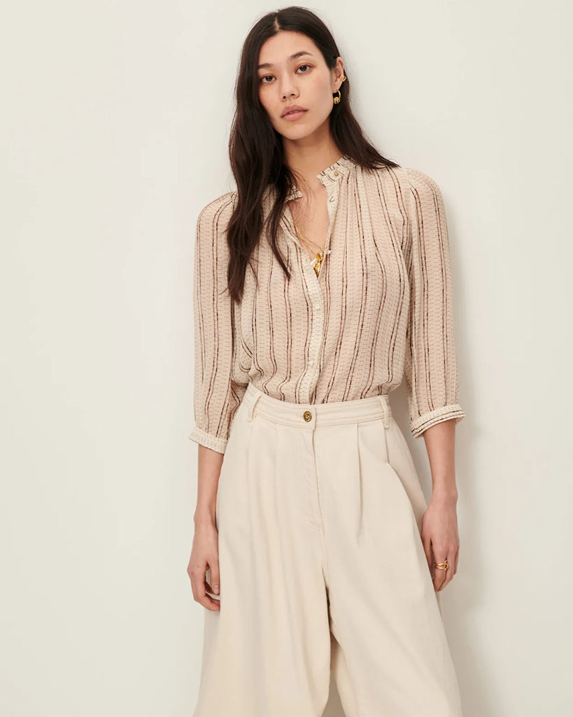 Efektowna, romantyczna Bluzka Lylee Whiplumikat francuskiej marki Sessun w drobne, metaliczne paski, z falbaniastym kołnierzykiem i szerokimi rękawami 3/4. Zapinana na guziki, z ozdobnym guzikiem przy kołnierzyku. Posiada marszczenia z przodu.