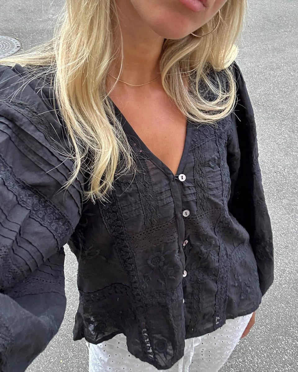 Luźna, kobieca koszula Mabel Almost Black marki SISSEL EDELBO z bufiastymi rękawami i dekoltem w serek z plisą zapinaną na małe guziki z masy perłowej i elastyczną pętelkę. Ozdobiona piękną koronkową taśmą i kwiatowym haftem w różnych miejscach. Wykonana w 100% z bawełny organicznej.

-Luźny fason

-Bufiaste rękawy

-Zamów bluzkę w swoim standardowym rozmiarze